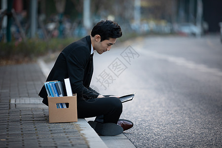 失业被炒鱿鱼的男性坐在街头图片
