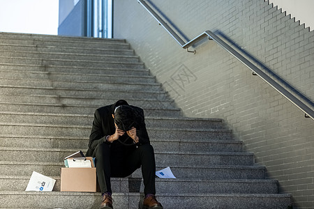 被辞退的商务男性失落的坐在楼梯上高清图片