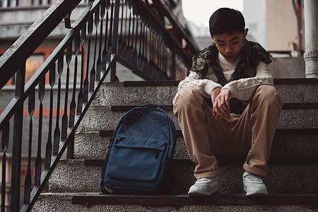 校园安全孤独的青少年坐在楼梯背景