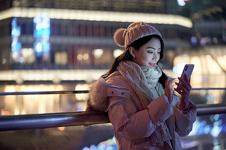 城市夜景人物夜晚使用手机自拍的冬季女性背景