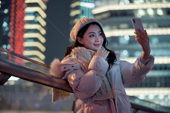 夜晚使用手机自拍的冬季女性图片