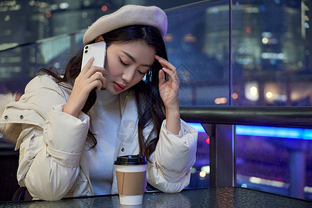 夜晚坐在咖啡厅打电话的女性图片