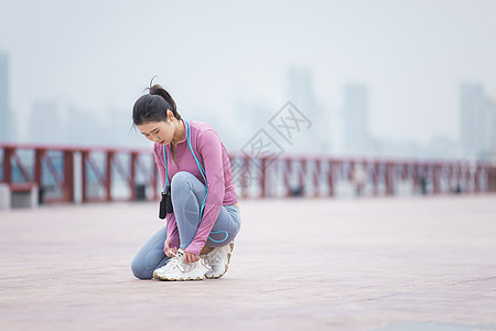 女性半蹲在跑道上系鞋带图片