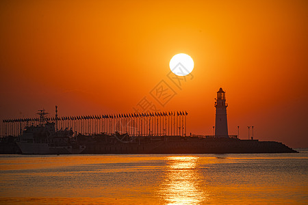 红彤彤的天空日出时红彤彤的海和伫立的灯塔背景