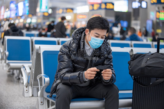 疫情期间戴着口罩候车的男性图片