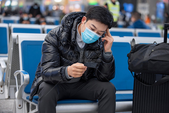 疫情期间戴着口罩候车的男性图片