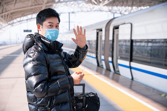 在站台等候列车进站的男性挥手打招呼图片