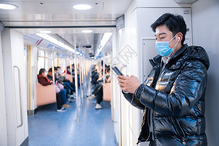 戴着口罩的男性在地铁上使用手机图片