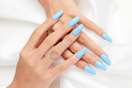 蓝色指甲女性纯色蓝色美甲特写握着丝绸背景