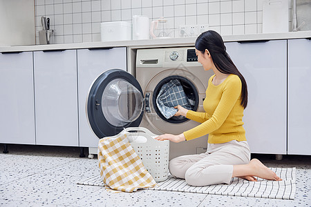 做家务的女性把脏衣服放入洗衣机图片