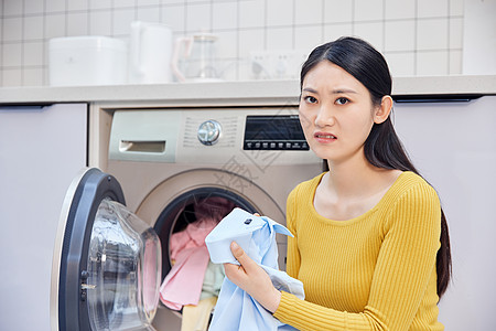 整理衣服做家务的女性把脏衣服放入洗衣机背景
