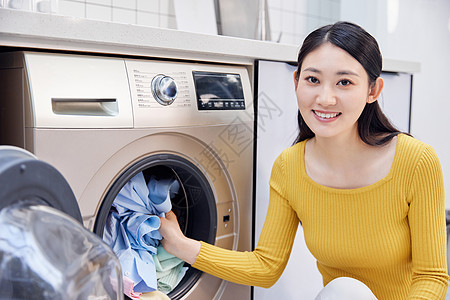 做家务的女性把脏衣服放入洗衣机图片