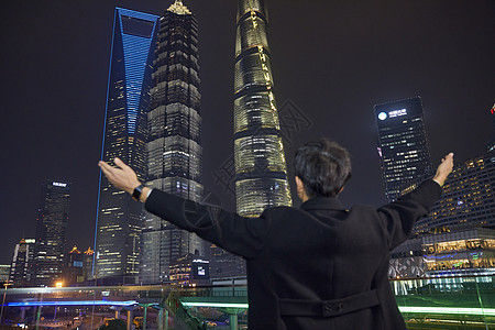 夜晚都市男青年拥抱城市背影图片