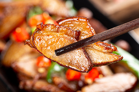 腊肉丁筷子夹起一片辣椒炒腊肉背景