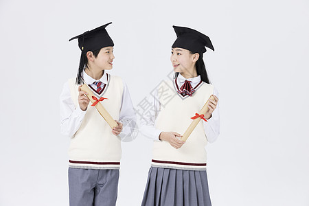两个毕业女孩毕业季头戴学士帽的中学生背景