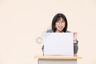 坐在课桌前展示白板的青春大学生图片