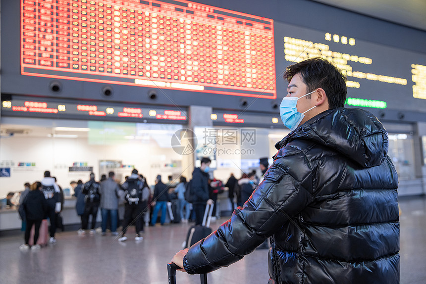 站在列车时刻表下的男性图片