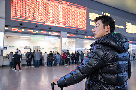 站在列车时刻表下的男性图片