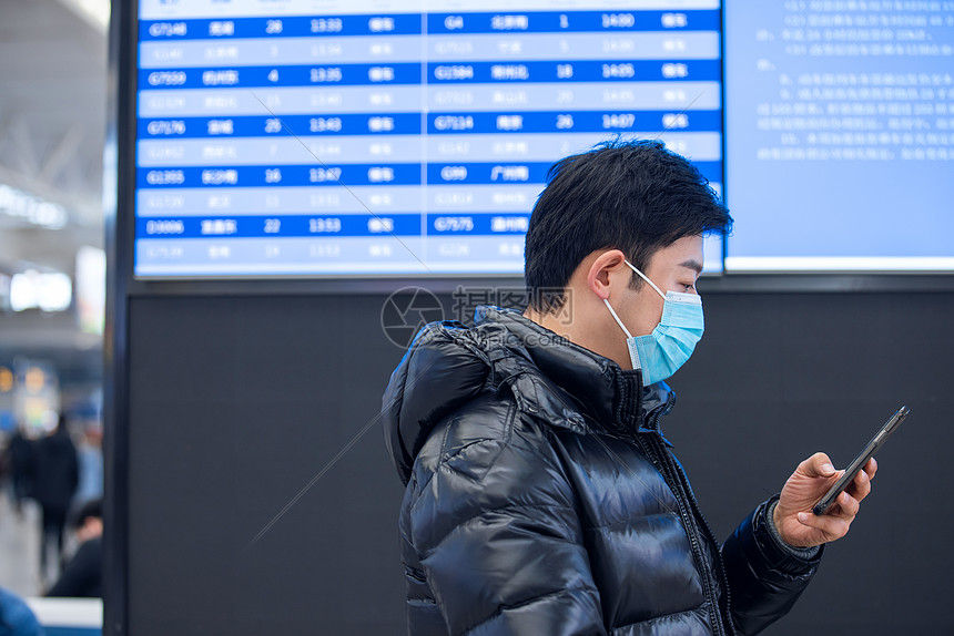 疫情期间戴着口罩使用手机的男性图片