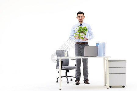 在办公室抱着一盆植物的职场男性图片
