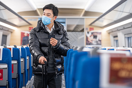 拿着车票在车厢内寻找座位的男性图片