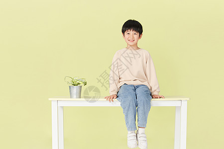 坐在桌子上微笑的小男孩图片