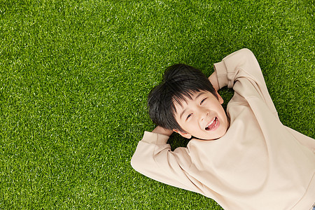 自由自在躺在草地玩耍的小男孩图片