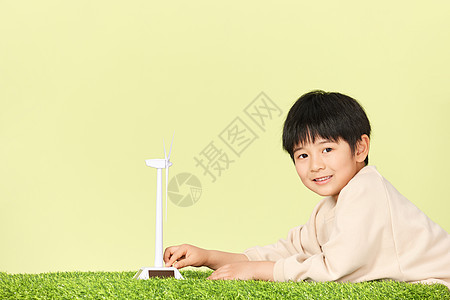 趴在草坪上的小男孩和风力发电机模型图片