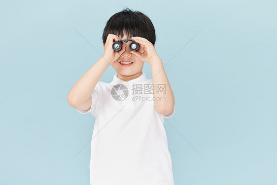 小男孩用望远镜探索远处图片