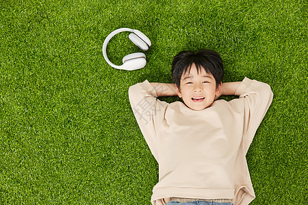 开心的在草坪上休息的小男孩图片