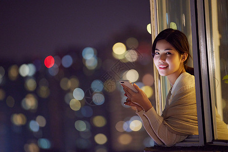 夜晚阳台深夜阳台玩手机的年轻女性背景