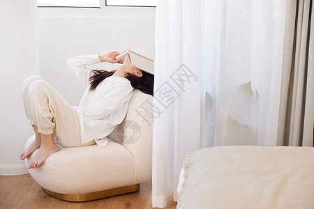 居家女性躺在沙发上用书盖着脸图片