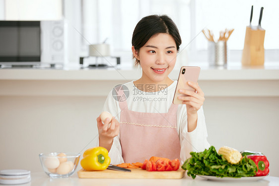 使用手机查看菜谱的年轻女性图片