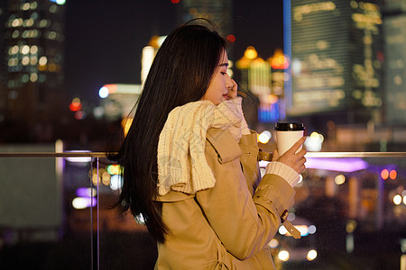 冬季夜晚都市女性人像手握咖啡杯图片