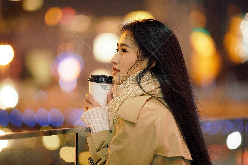 冬季夜晚都市女性手握咖啡杯侧脸人像图片