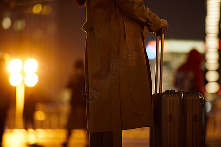 夜晚都市女性手提行李箱走在路上图片