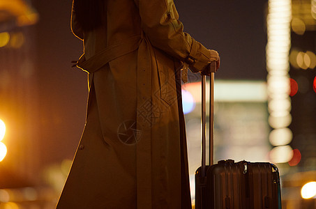 夜晚都市女性手提行李箱走在路上图片
