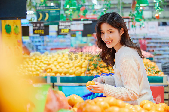 超市购物挑选橘子的青春女性图片