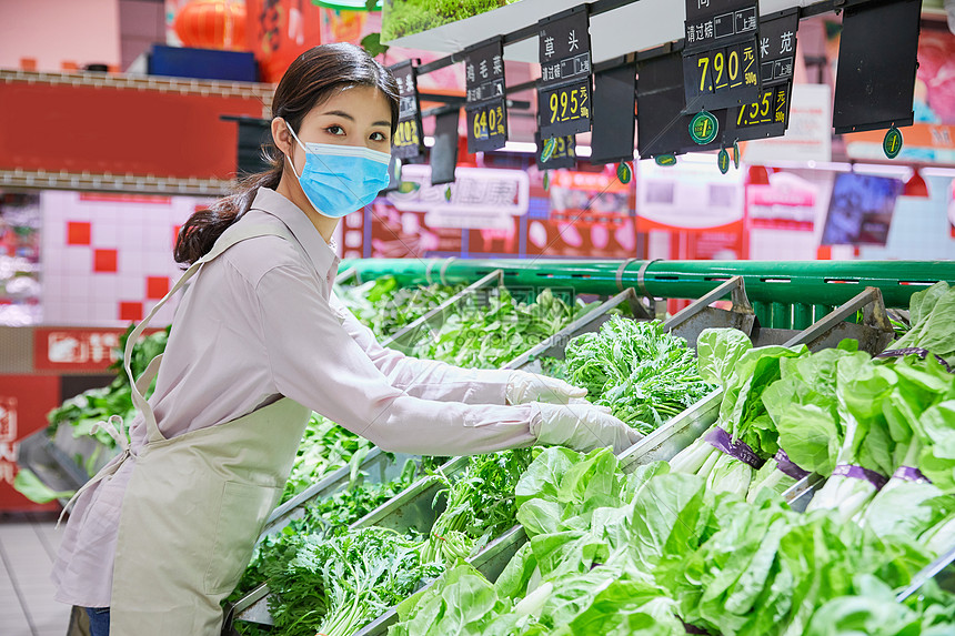 佩戴口罩的超市服务员整理蔬菜区图片