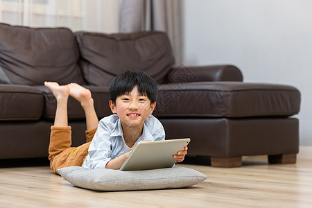 小男孩趴在地上使用平板电脑图片