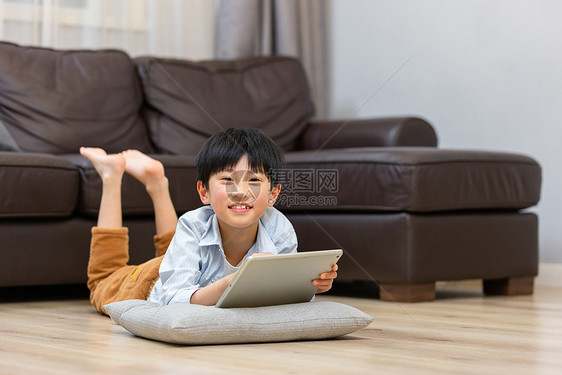 小男孩趴在地上使用平板电脑图片