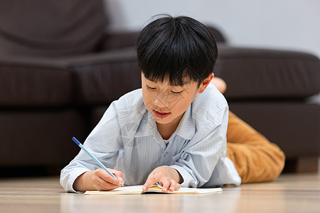 小孩阅读小男孩趴在地上做作业背景