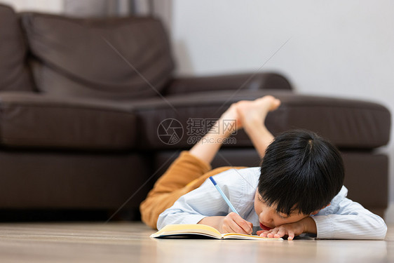 趴在地上写作业的小男孩图片