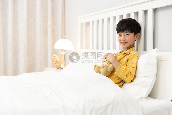 小男孩抱着玩偶熊躺在床上图片