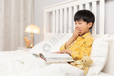 在床上看书犯困的小男孩图片