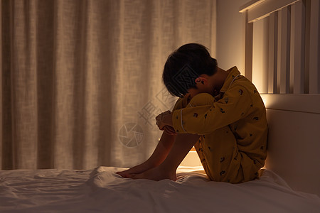 坐在床上哭泣的小男孩高清图片