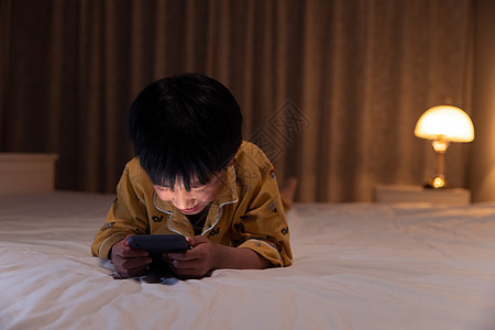 小男孩在黑暗中玩手机图片