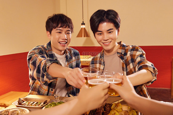 青年男性朋友欢乐喝啤酒撸串图片