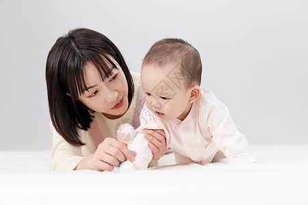 漂亮妈妈喂奶瓶月嫂与新生婴儿宝宝玩耍背景