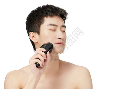 男青年使用电动剃须刀背景图片